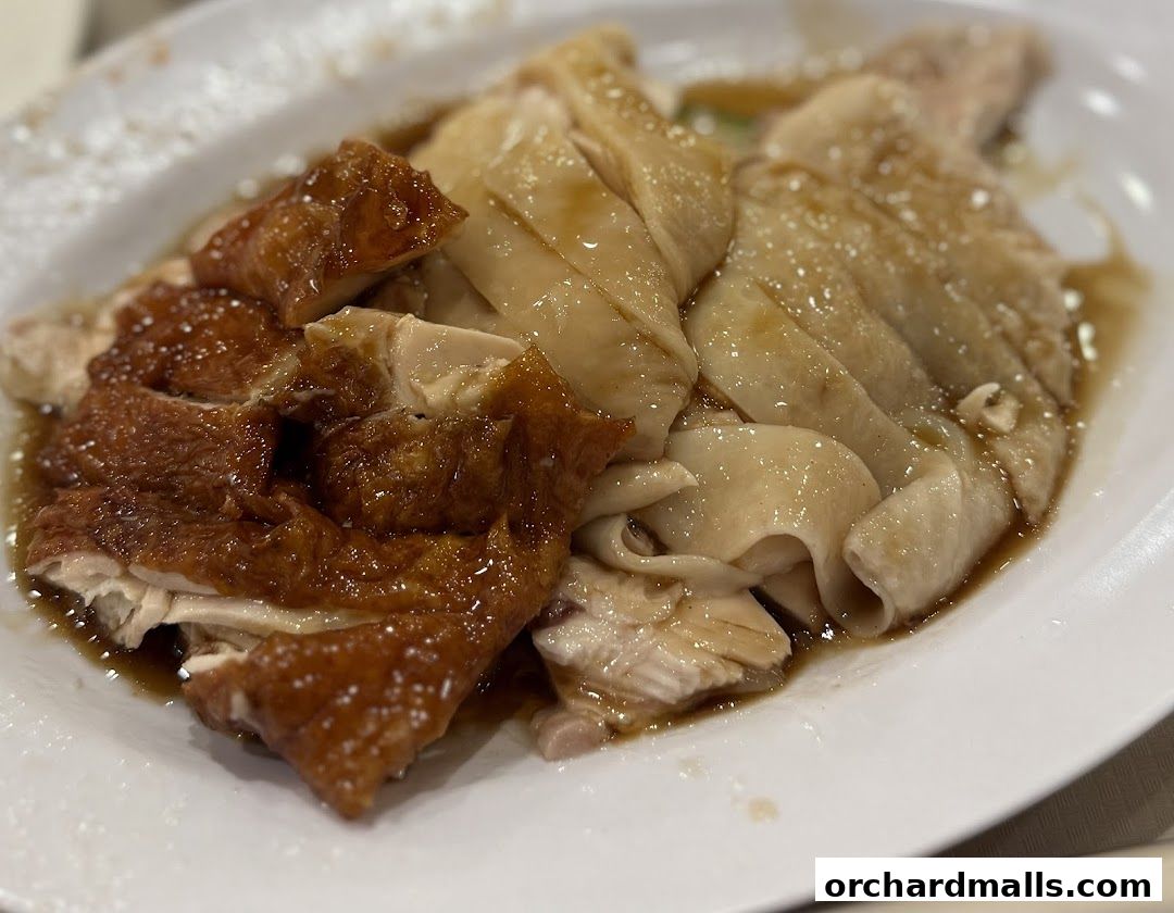 A plate of succulent Hainanese chicken, featuring both roasted and steamed varieties.