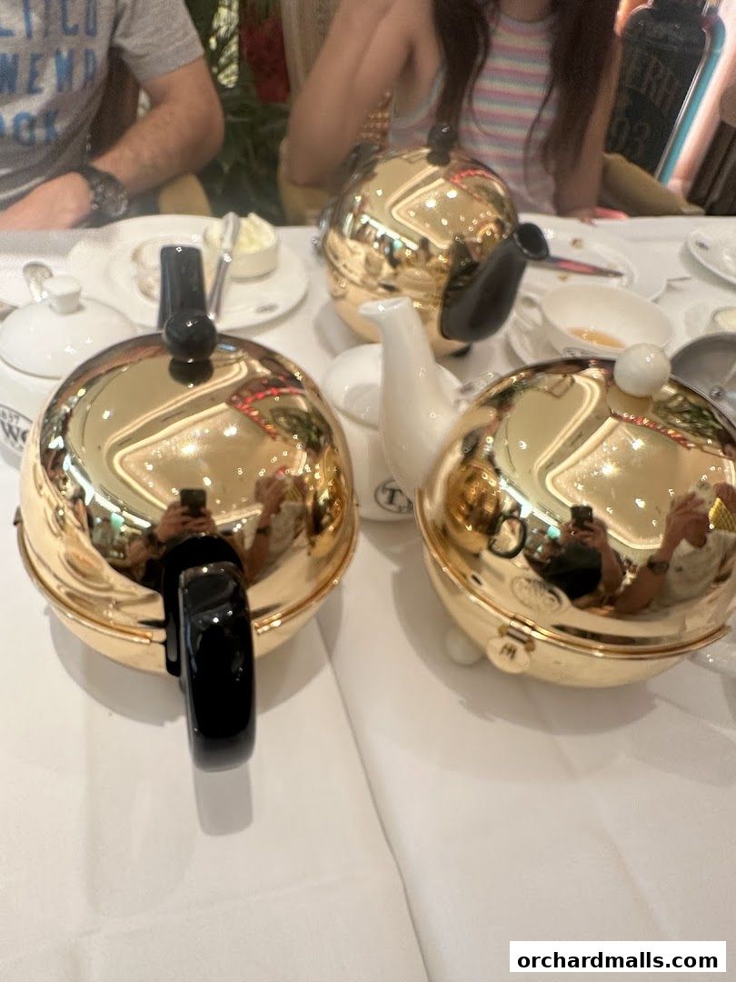 Close-up of golden teapots and people at a table, likely a restaurant.