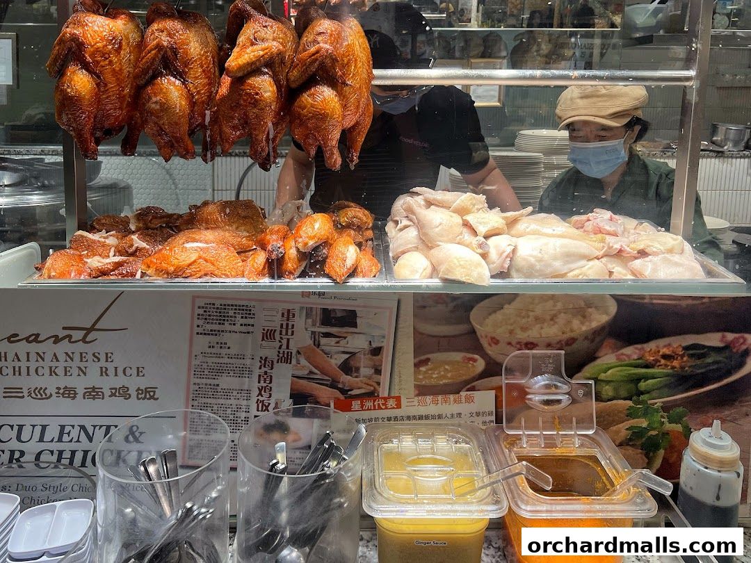 A display of roasted and raw chicken, with condiments and rice in the background.