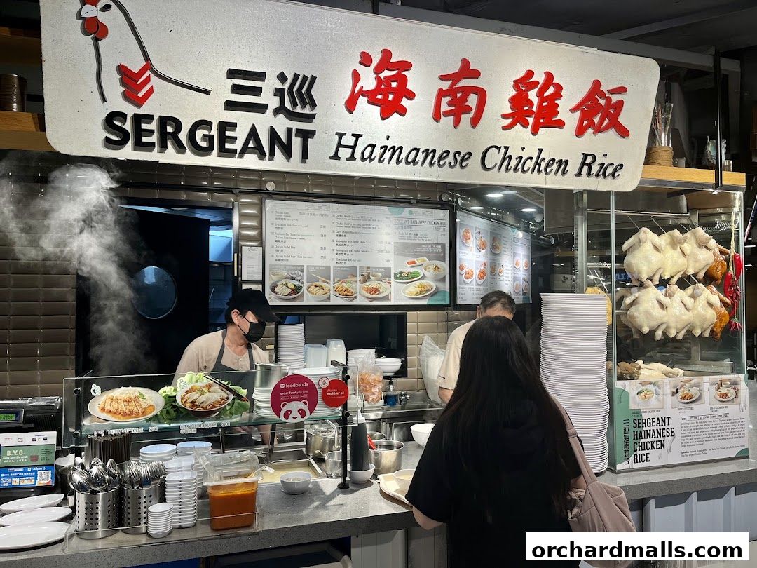 A busy counter at Sergeant Hainanese Chicken Rice with staff serving customers.