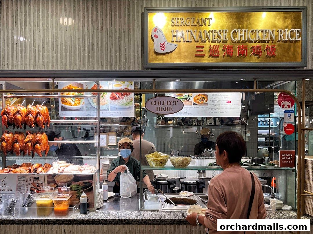 A customer orders at Sergeant Hainanese Chicken Rice, with roasted chickens displayed.