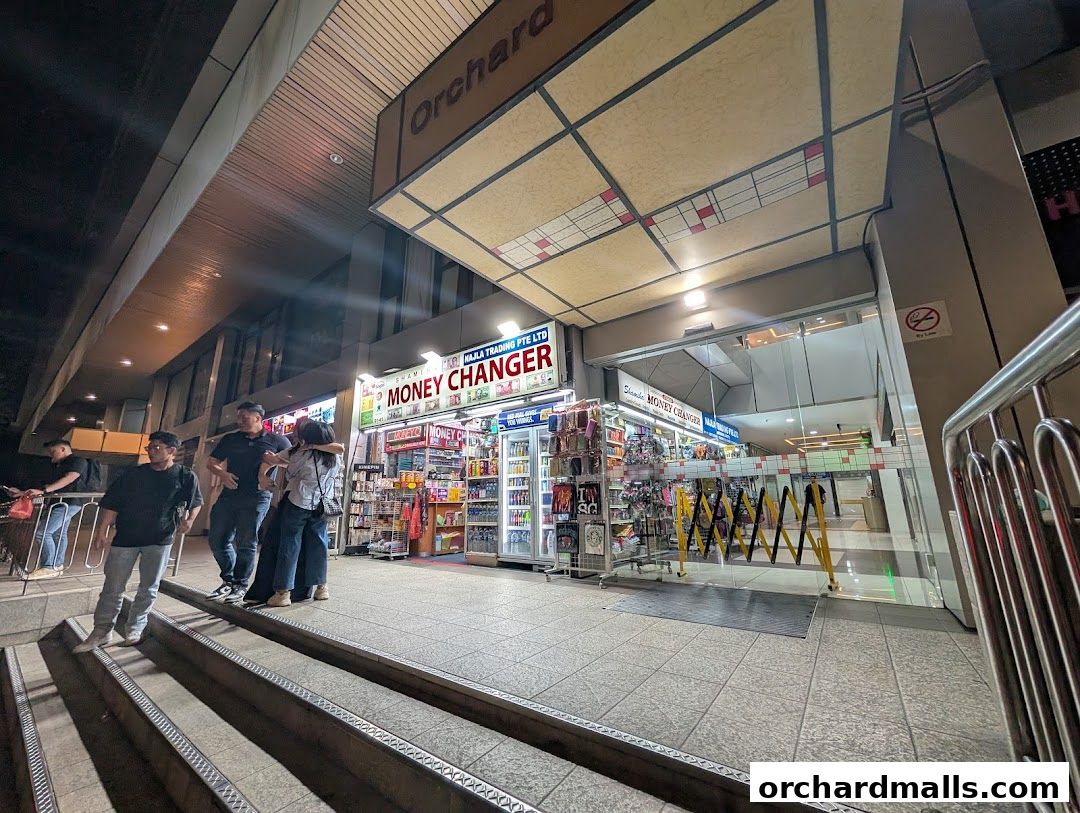 Shamiha Money Changer shop front with people standing outside at night.