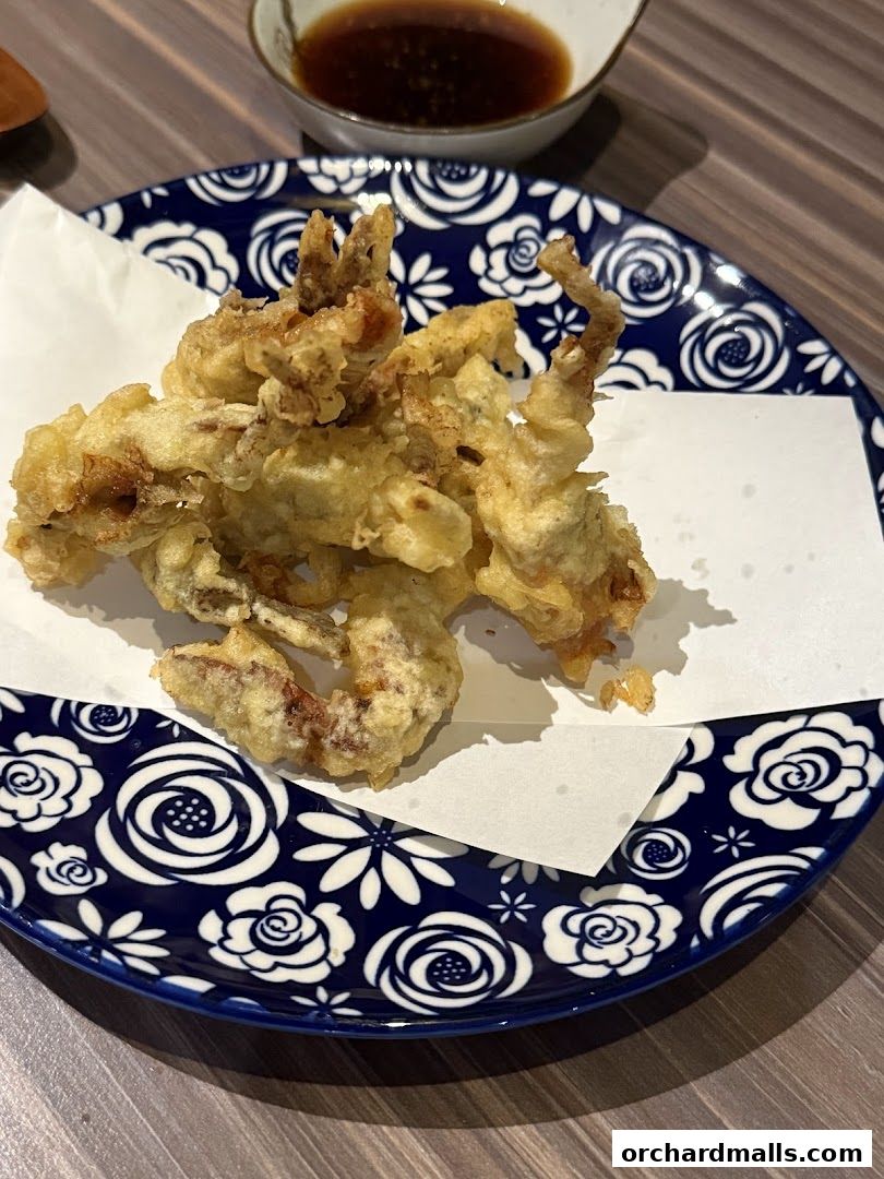 A plate of crispy fried seafood with a side of dipping sauce.
