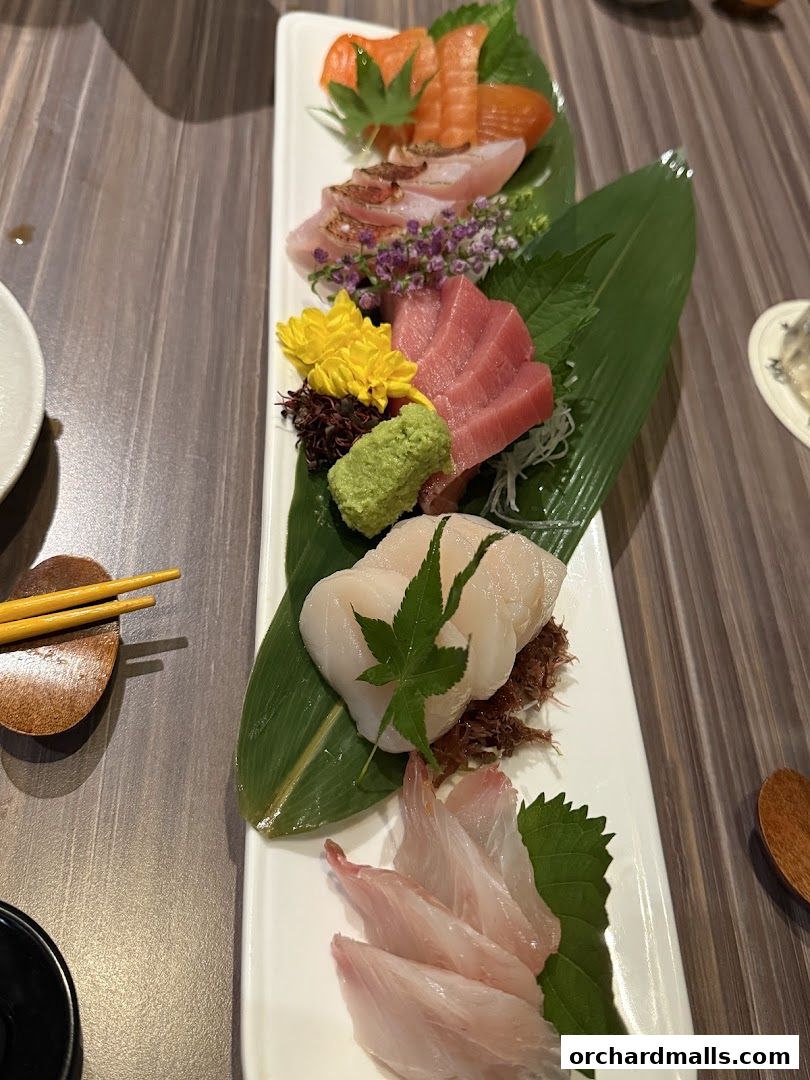 A platter of assorted sashimi, including salmon, tuna, and white fish, beautifully presented with wasabi and garnishes.