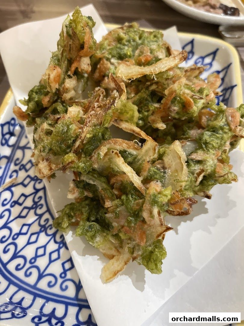 A close-up of crispy fried tempura with shrimp and vegetables on a decorative plate.