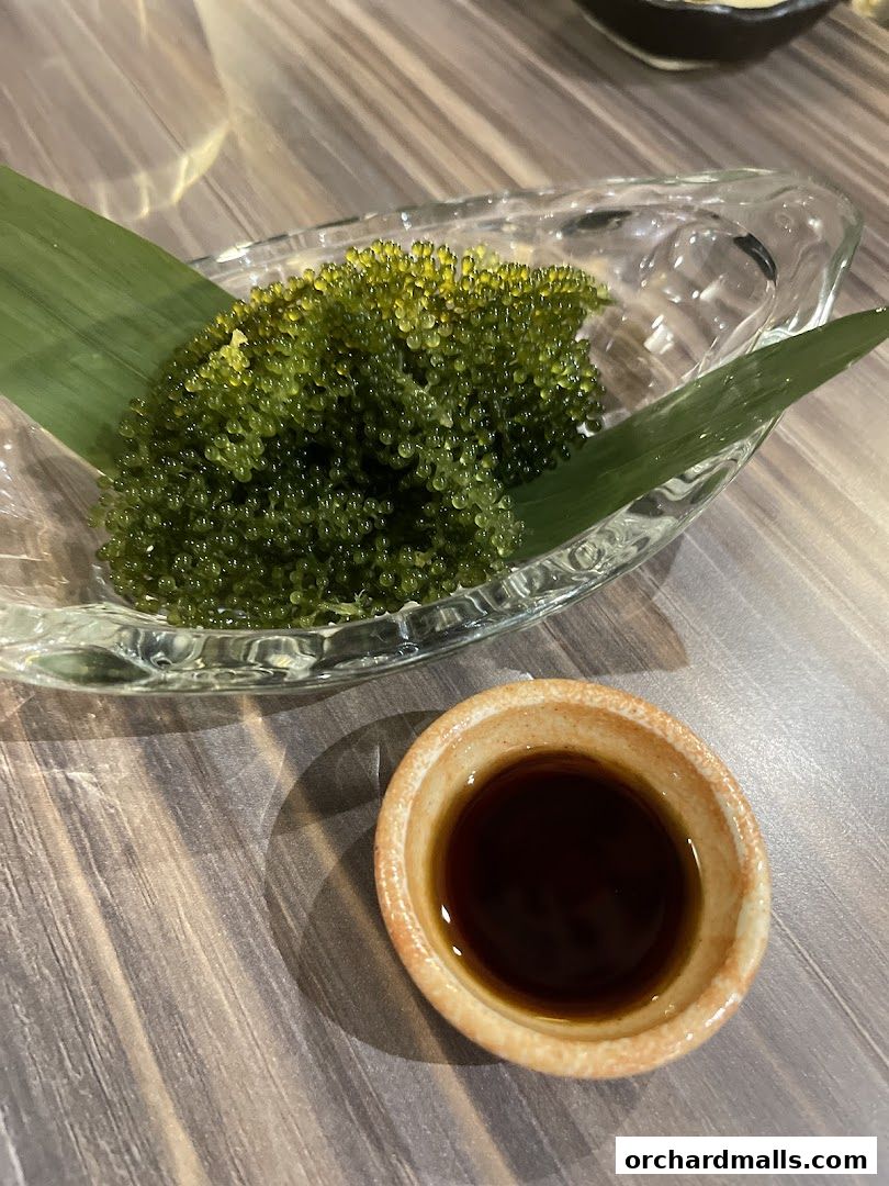A close-up of sea grapes served with soy sauce in a small dish.