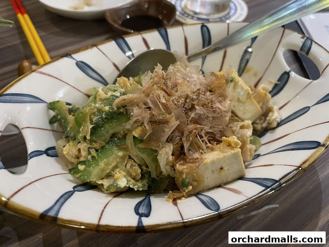 A close-up of a dish featuring bitter melon, tofu, and bonito flakes.