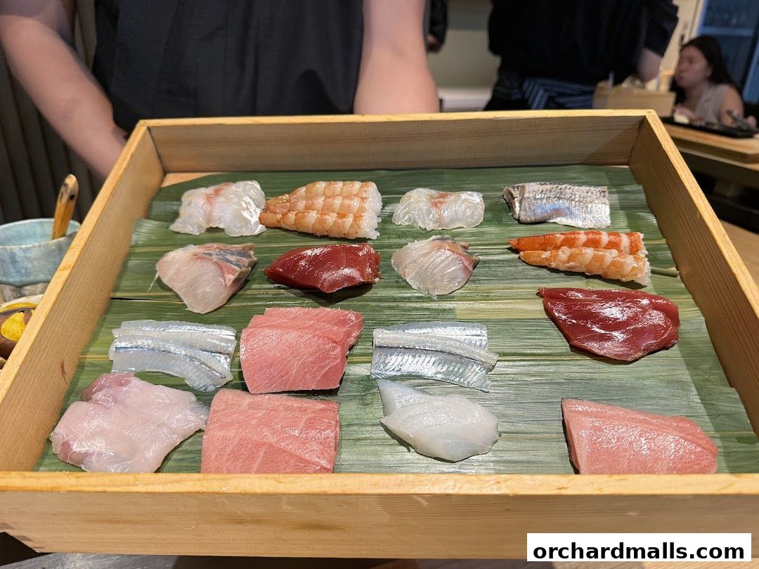 A wooden tray filled with various types of fresh sashimi and shrimp.