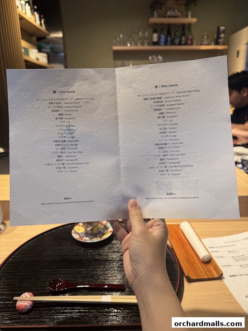 A person holds open a Japanese restaurant menu featuring two course options.