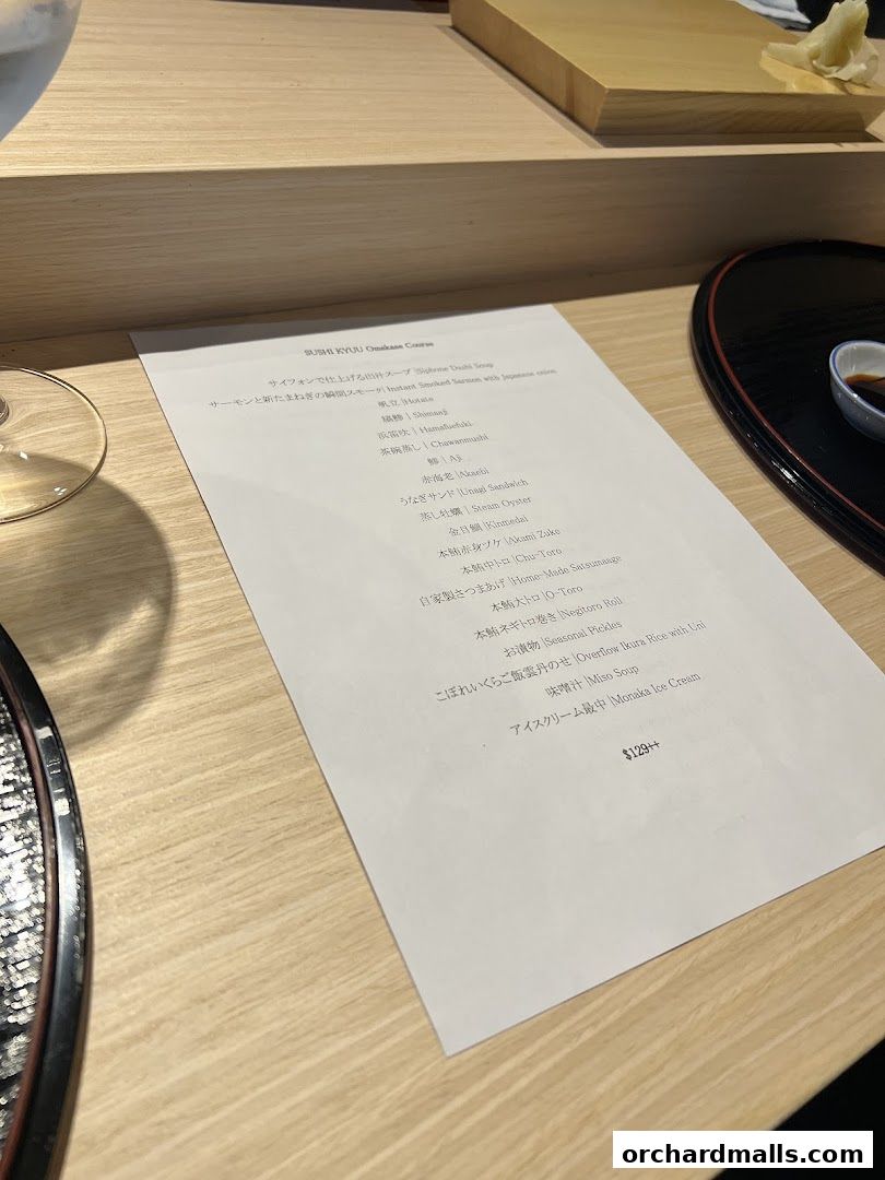 A menu for Sushi Kyuu Omakase Course is laid out on a wooden table.