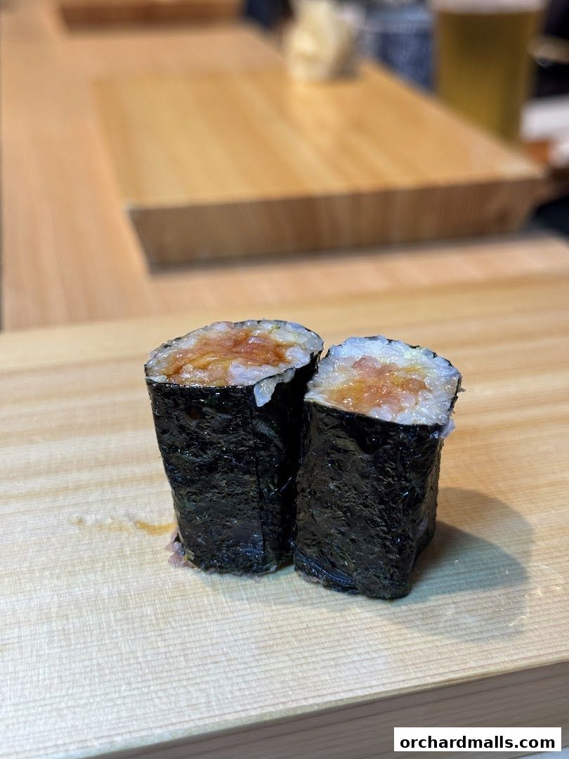 Two pieces of sushi roll with nori seaweed and filling on a wooden board.