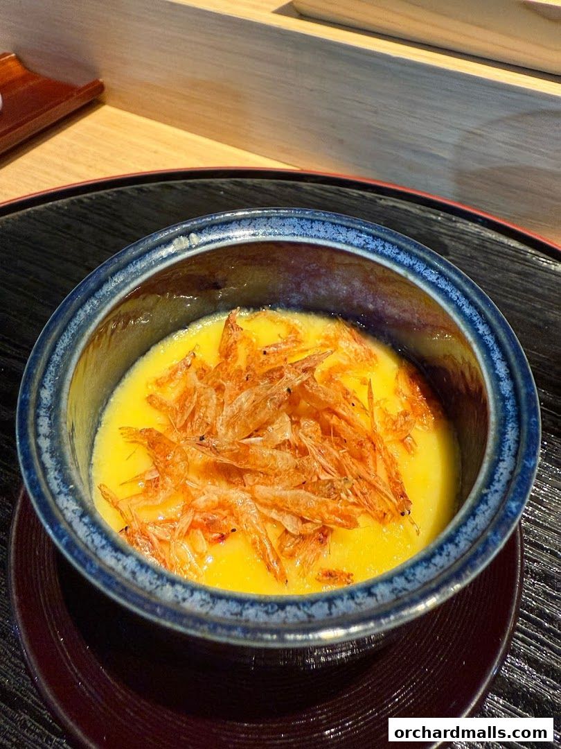 A close-up of a savory egg custard dish topped with small dried shrimp.