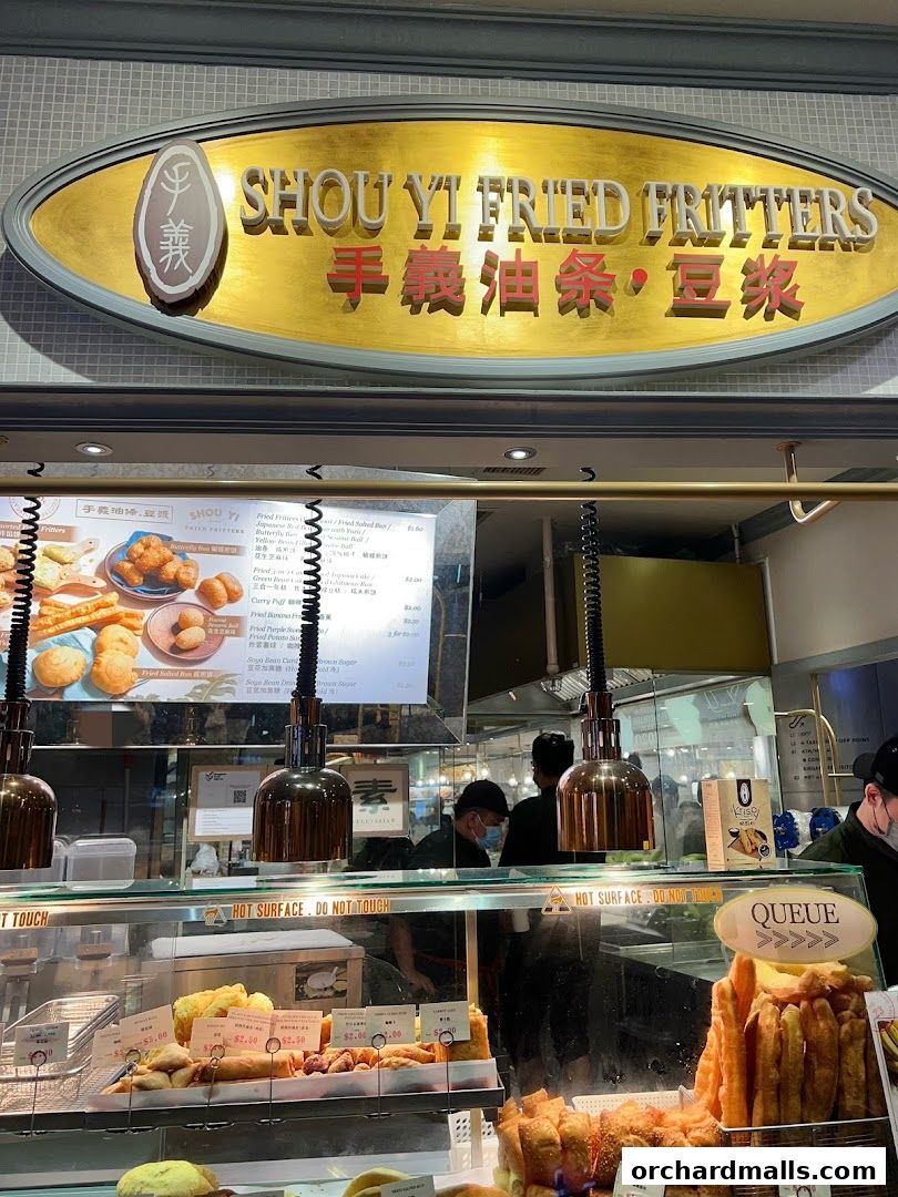 A shop front for Shou Yi Fried Fritters, displaying a menu and various fried food items.