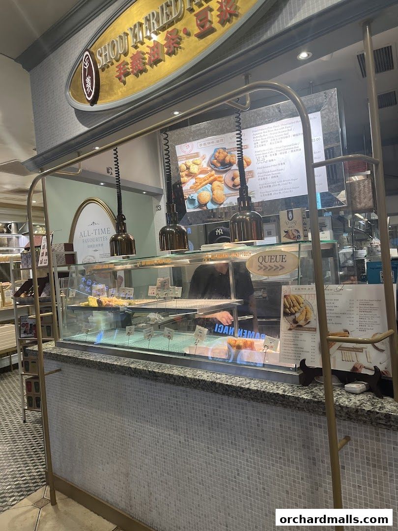 A display counter at Shou Yi Fried Fritters, showcasing various fried snacks and a menu board.