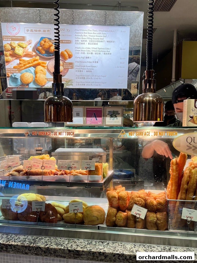 A display of fried fritters and other snacks with a menu board above.