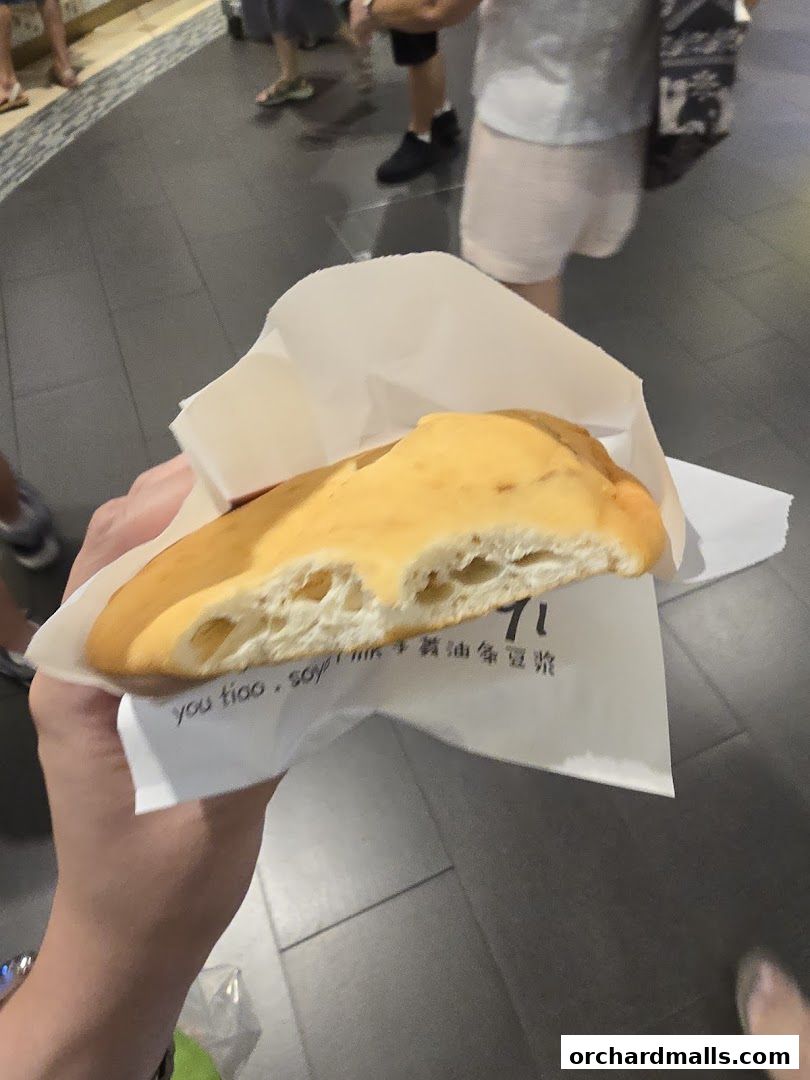 A person holds a half-eaten fried fritter wrapped in paper with Chinese characters and the number 71.