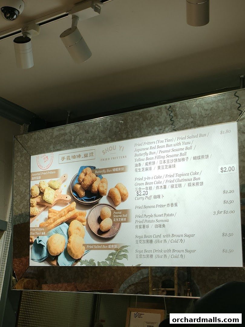 A menu board displaying various fried fritters and drinks with prices.