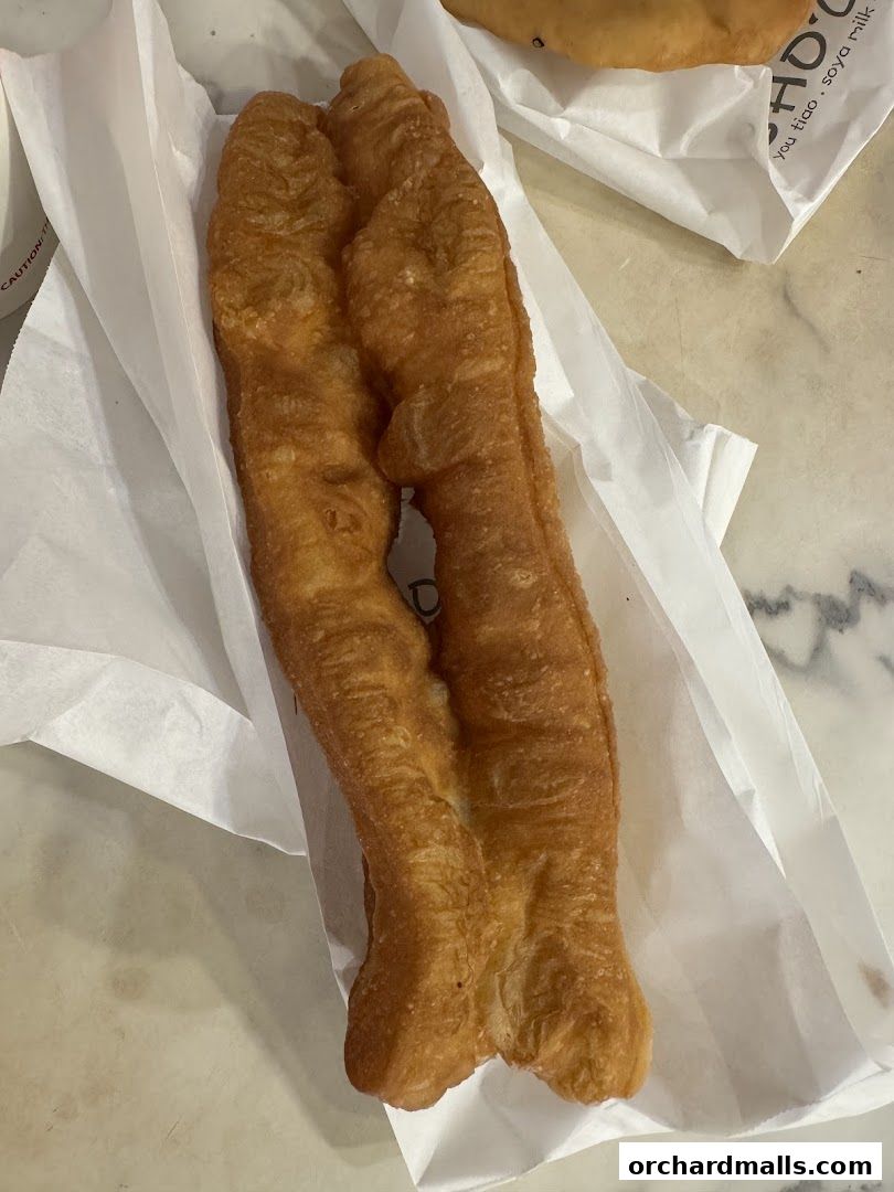 A close-up shot of two golden-brown fried dough sticks, commonly known as Youtiao.