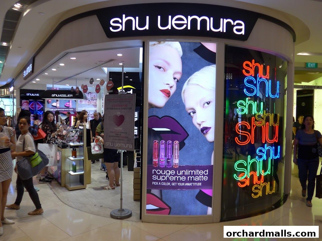 The Shu Uemura shop front with neon signs and makeup displays, featuring models and lipstick.