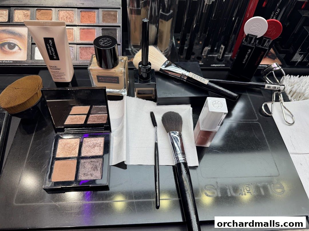 A collection of Shu Uemura makeup products and applicators laid out on a black surface.