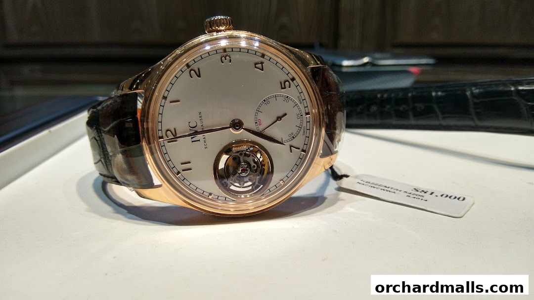 A close-up of a luxurious rose gold watch with a white dial and a tourbillon.