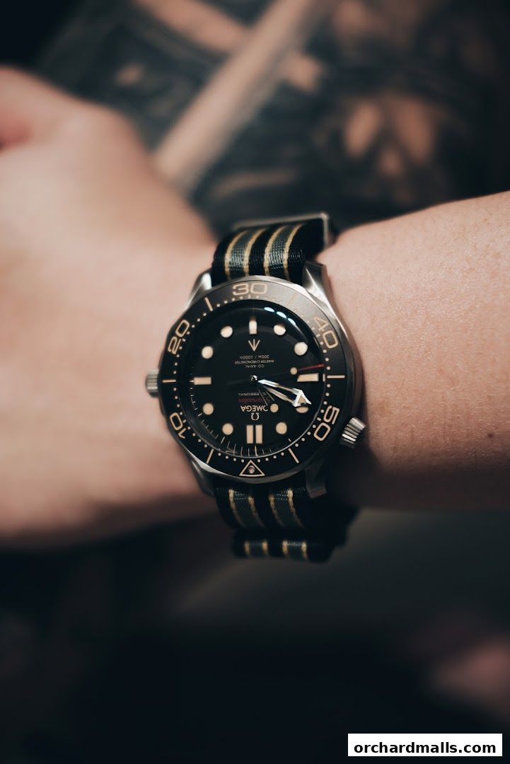 Close-up of an Omega Seamaster watch with a striped NATO strap on a wrist.