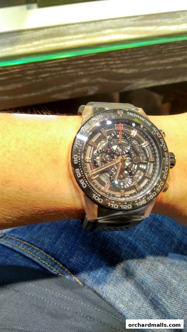A close-up shot of a man wearing a luxury watch with a complex dial and tachymeter.