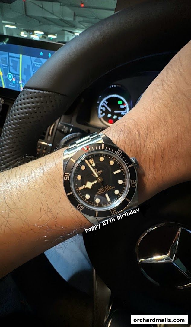 A person wearing a Tudor watch inside a car, celebrating a birthday.
