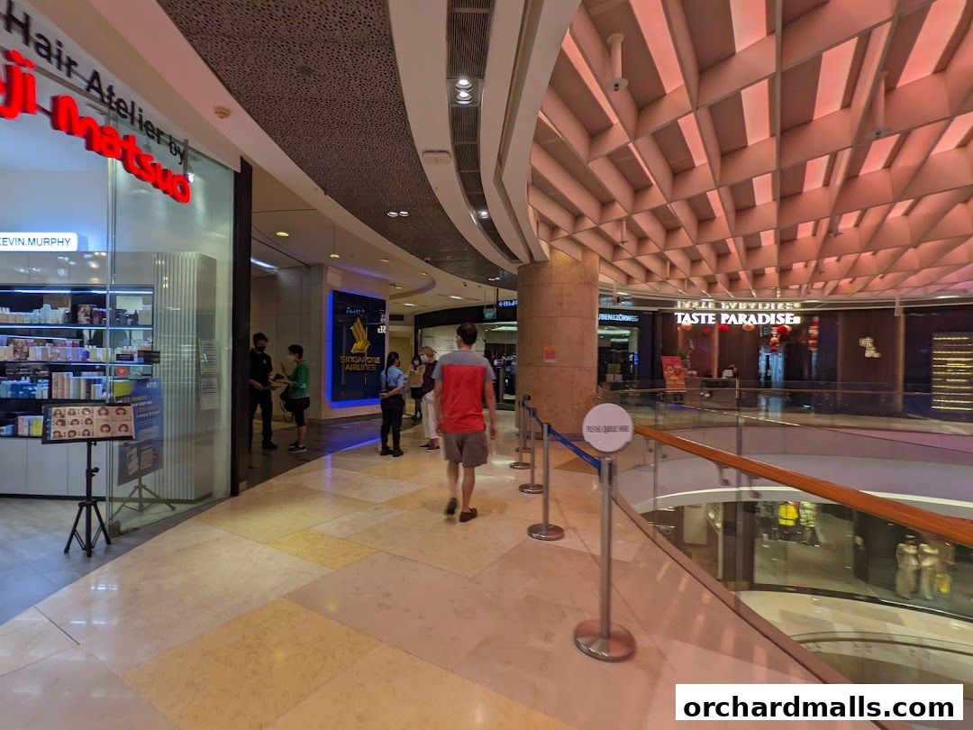 A view of a shopping mall corridor with shops and people walking.