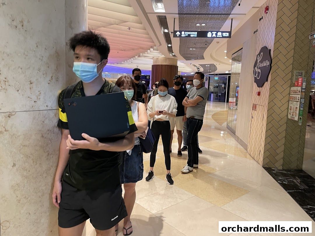 People queuing in a mall hallway, with a Singapore Airlines Service Centre sign visible.