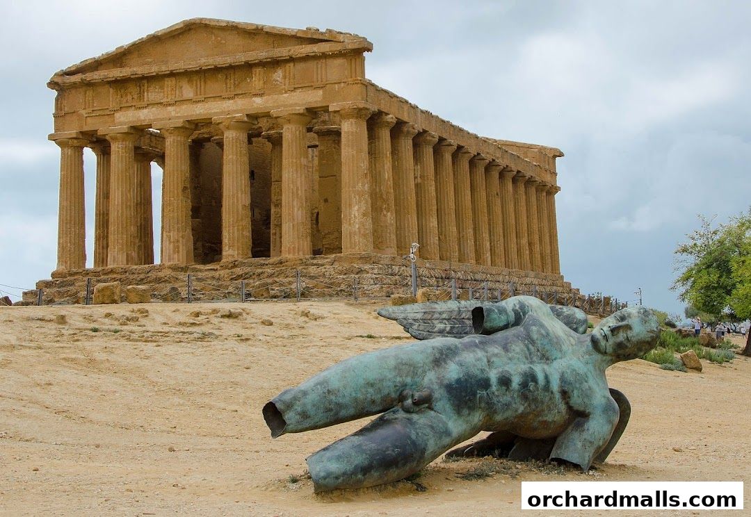Ancient Greek temple ruins with a fallen bronze statue in the foreground.