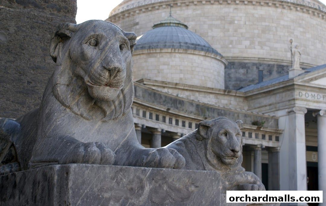 Stone lion statues guard the entrance of a grand building with a dome.