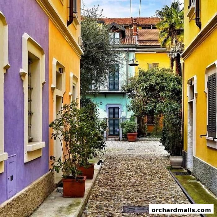 A charming cobblestone alleyway lined with vibrantly colored buildings and lush greenery.