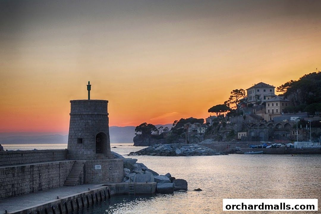 A picturesque coastal town with a lighthouse at sunset.