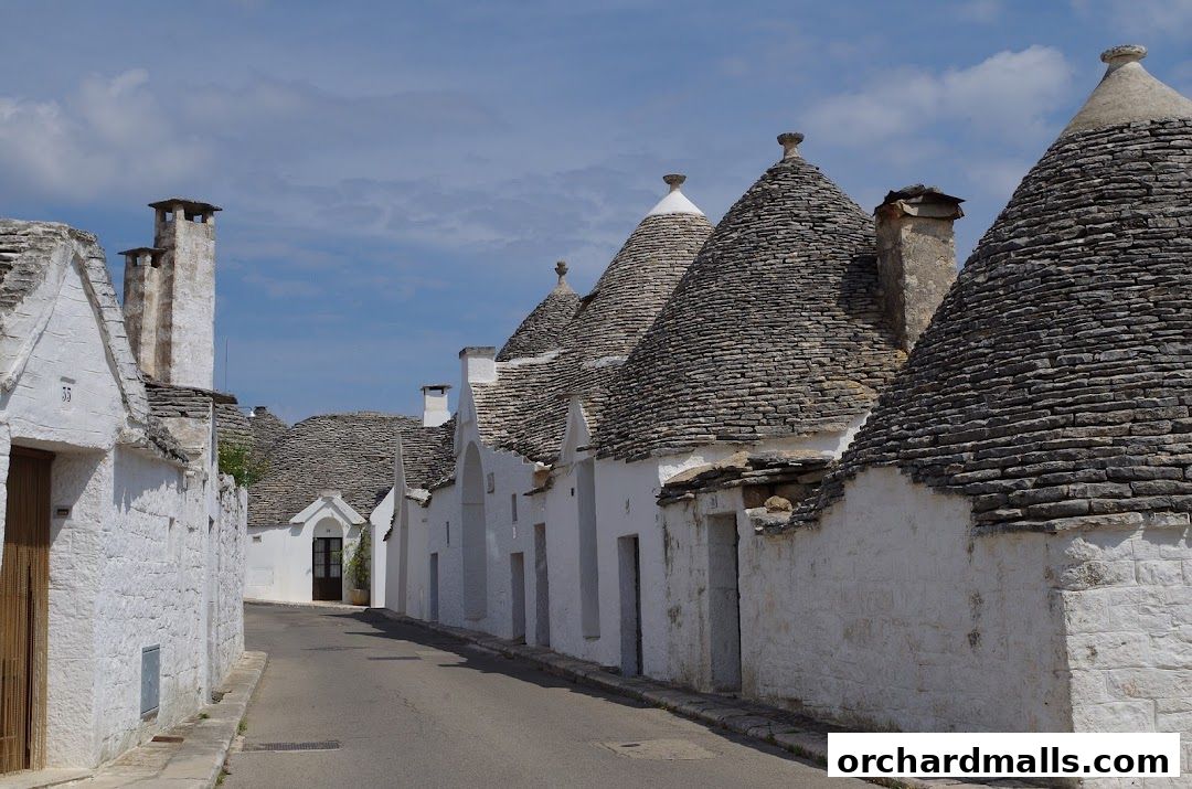A street lined with traditional white trulli houses with conical stone roofs.