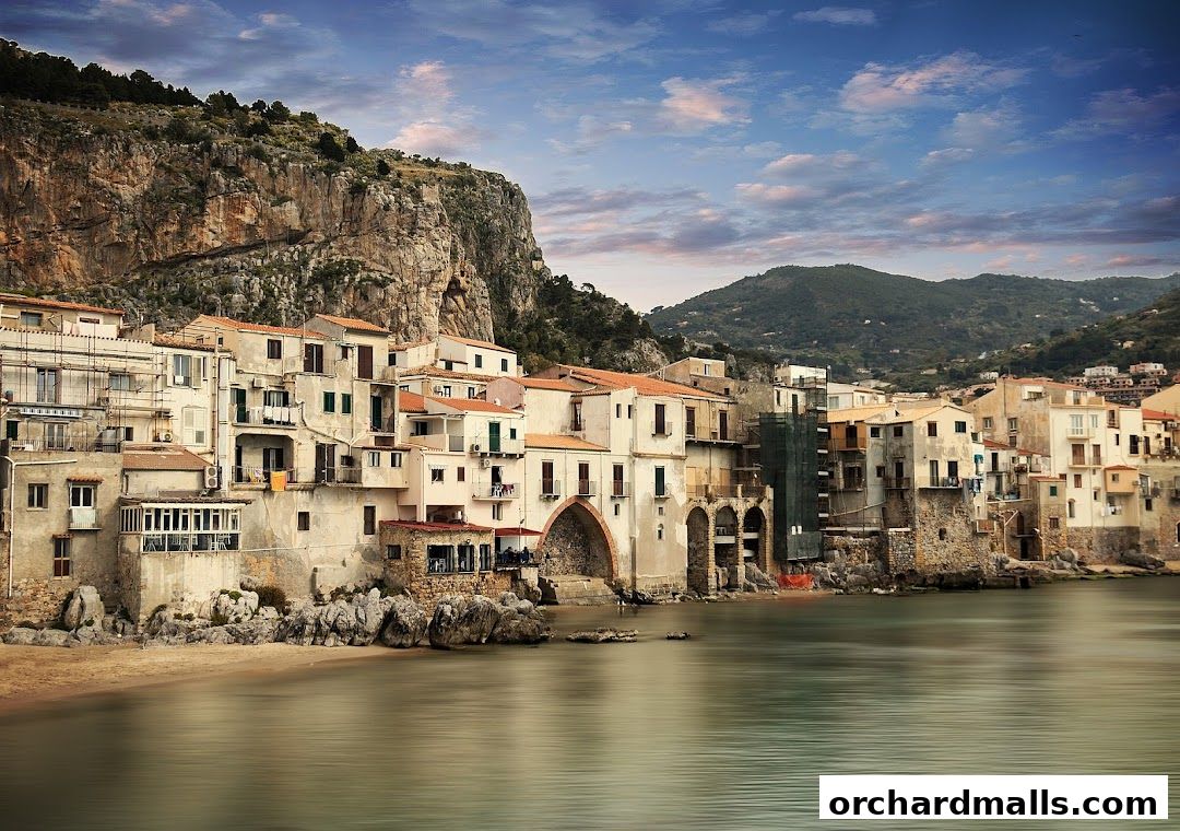 A picturesque coastal town with buildings nestled against a rocky cliff overlooking the sea.