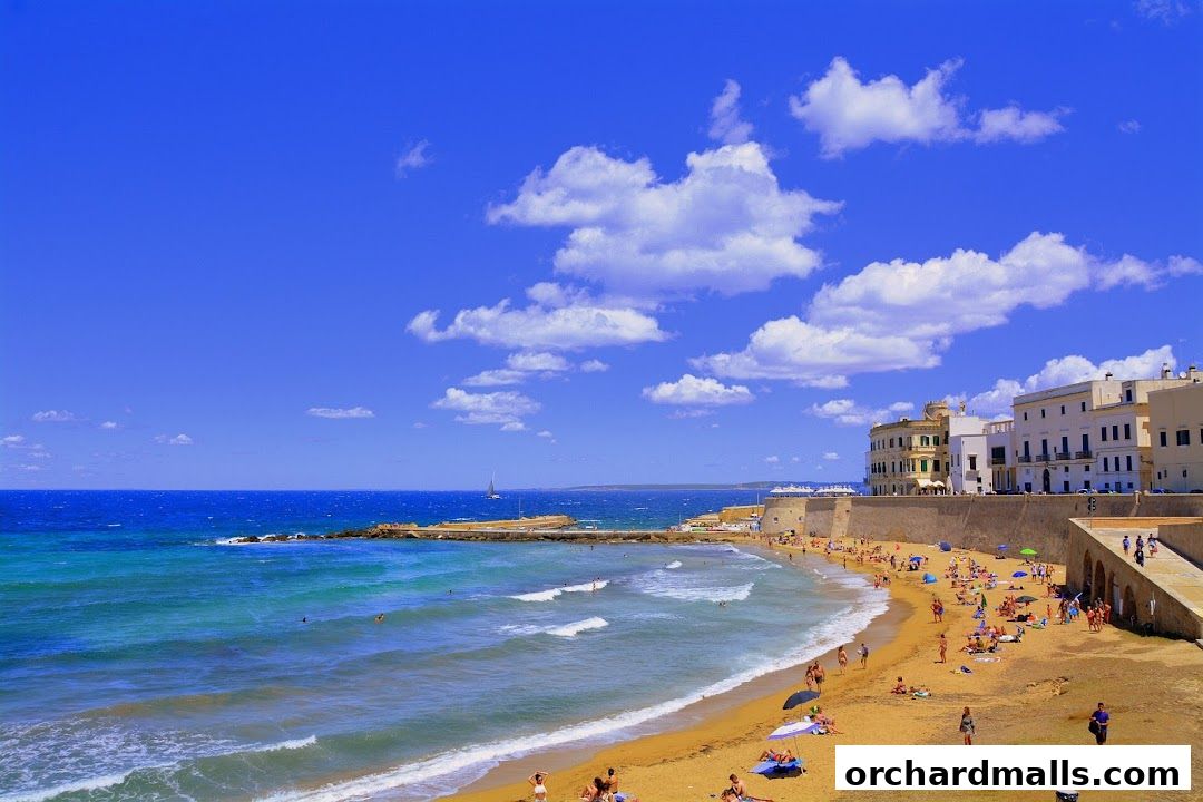 A vibrant beach scene with people enjoying the sun and sea under a clear blue sky.