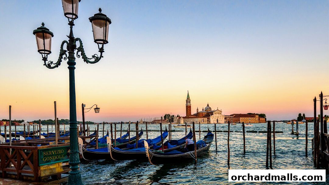 Venetian gondolas docked at sunset with historic buildings in the background.