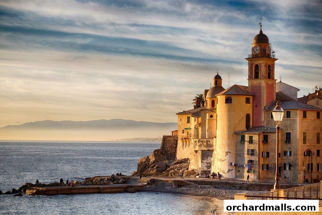 A picturesque Italian coastal town with historic buildings and a clock tower by the sea.
