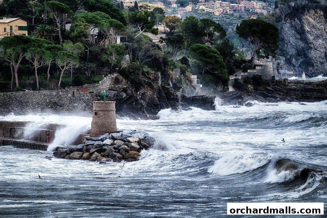 A lighthouse and rocky shore with waves crashing during a storm.