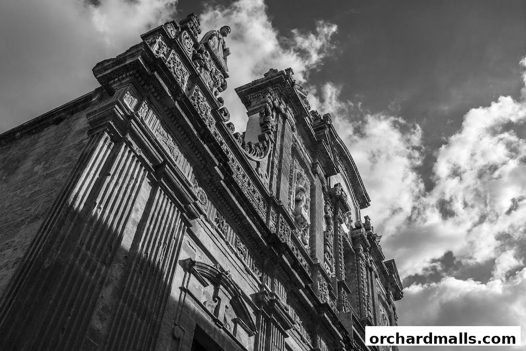 Ornate facade of a historic building with intricate carvings against a cloudy sky.