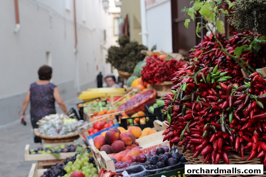 A vibrant display of fresh produce, including chilies, fruits, and vegetables, at an outdoor market.