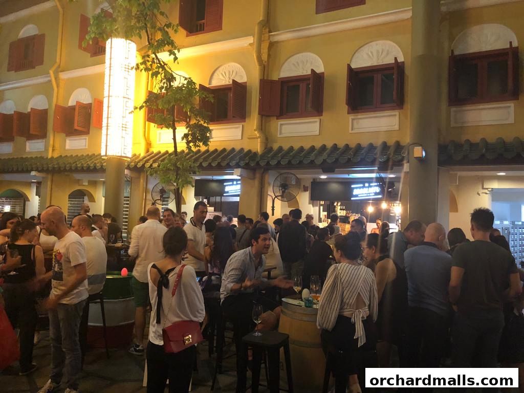 A lively outdoor gathering at the Singapore Italian Association with people socializing and enjoying the evening.
