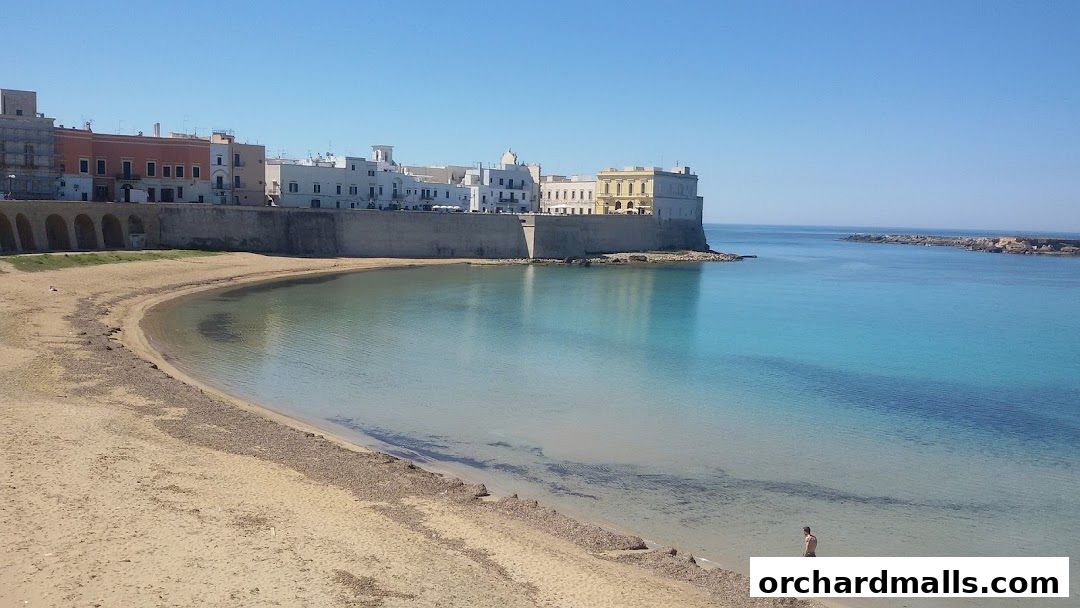 A scenic view of a coastal town with buildings along the shore and a clear blue sea.