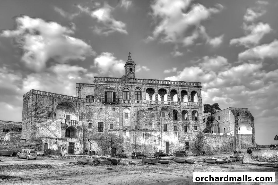 Historic Italian building with arched windows and balconies, boats on shore.