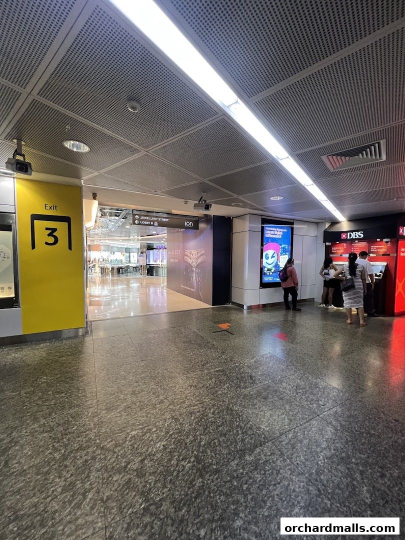 An interior view of a shopping mall with an exit sign and a DBS bank ATM.