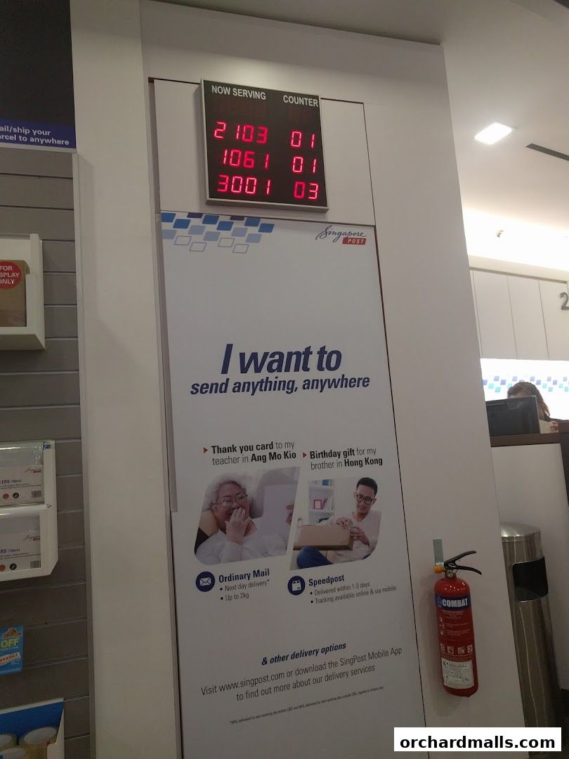 Singapore Post branch with a digital display showing queue numbers and a promotional banner.