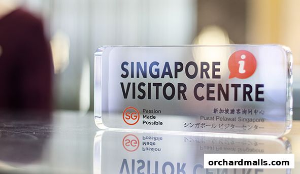 A clear acrylic sign for the Singapore Visitor Centre with multilingual text.