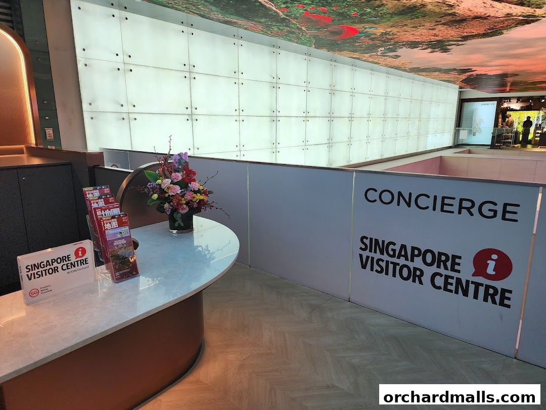 The Singapore Visitor Centre at ION Orchard features a concierge desk with brochures and a floral arrangement.
