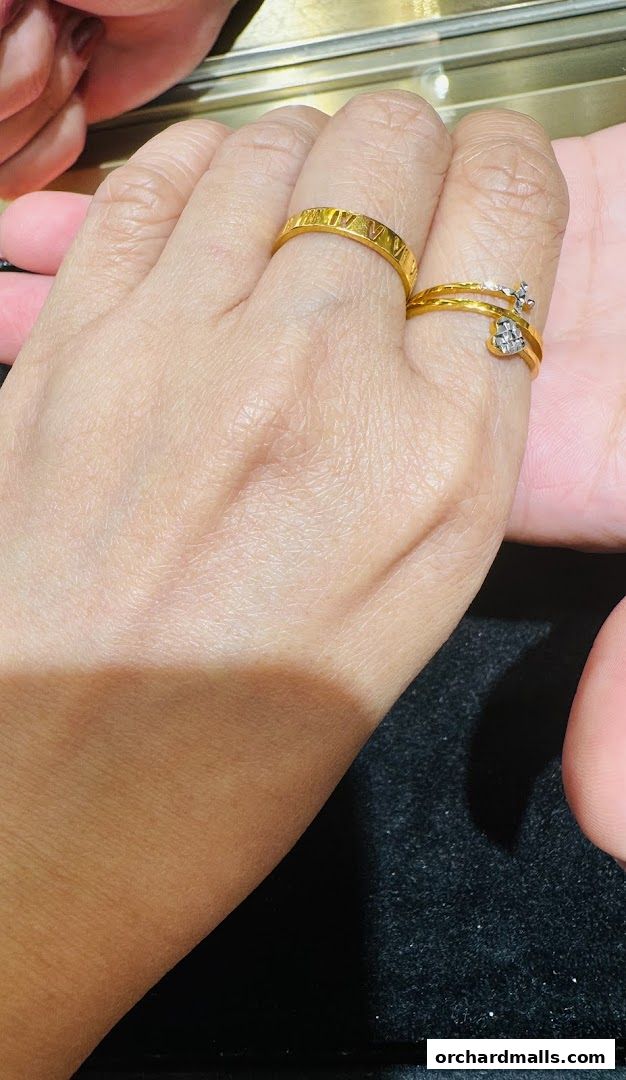 Close-up of hands wearing elegant gold rings, one with Roman numerals and another with a diamond cross.